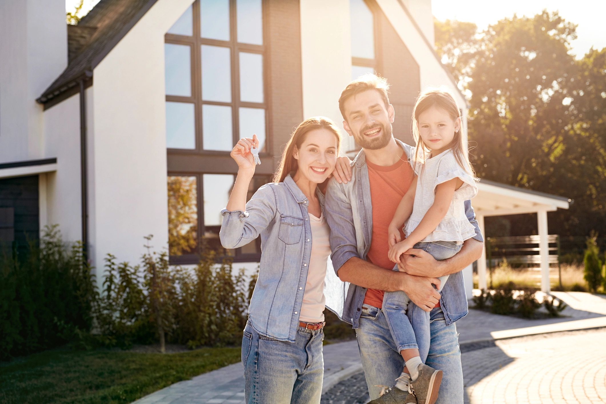Family standing outside their new home holding keys